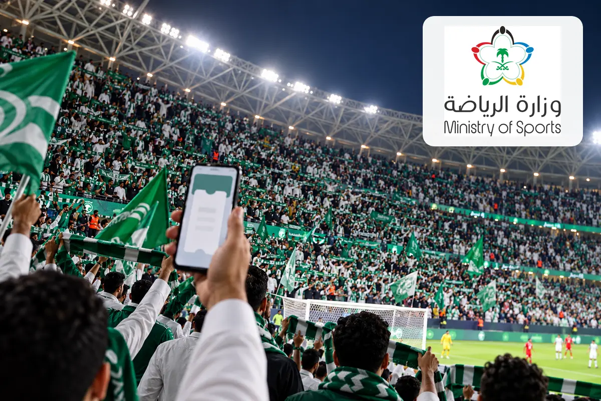 Saudi football supporters in a packed stadium using a generic digital ticket, with the genuine Ministry of Sport logo visible