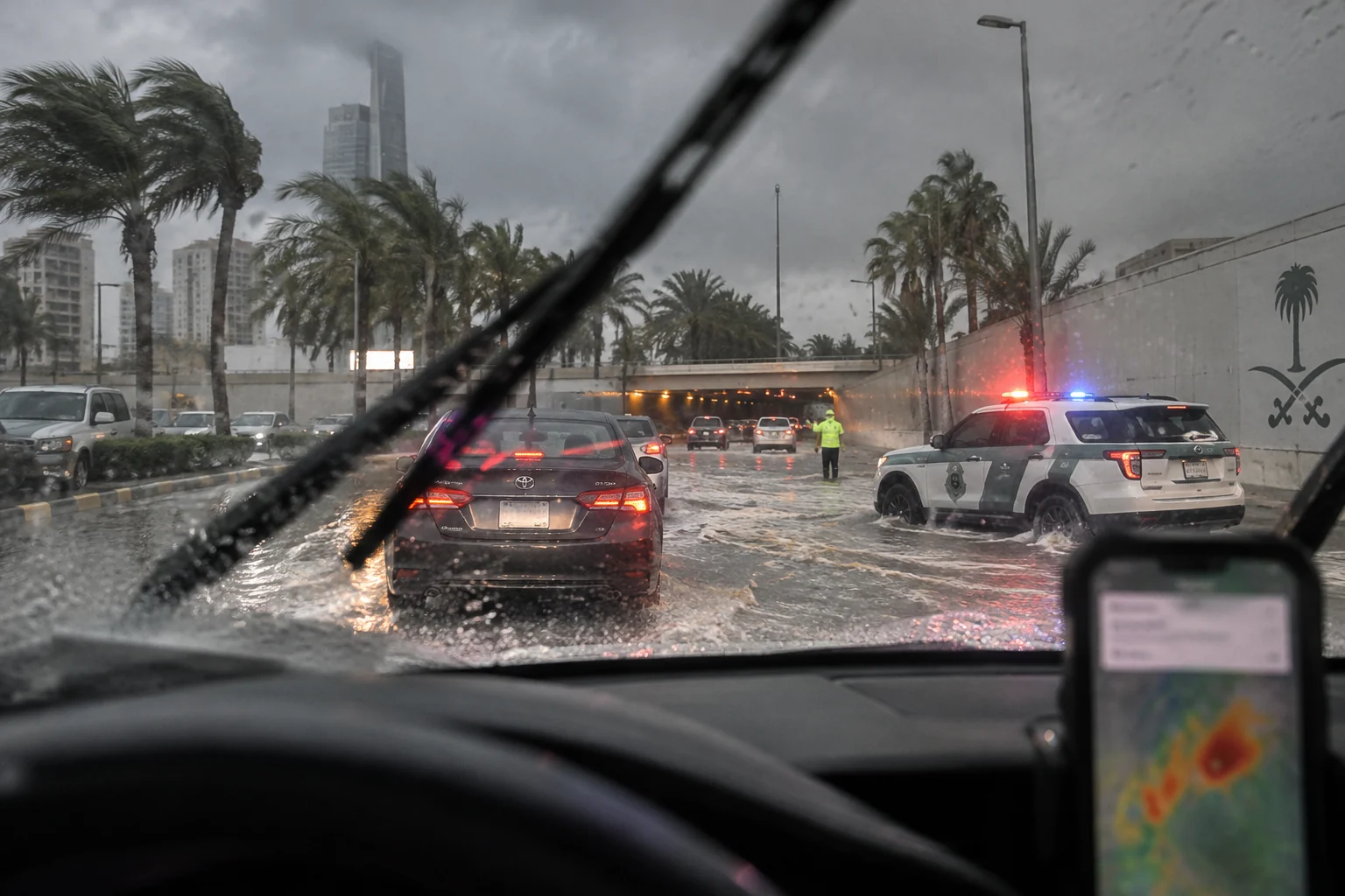 Editorial illustration of traffic moving cautiously on a rain-soaked Saudi urban road