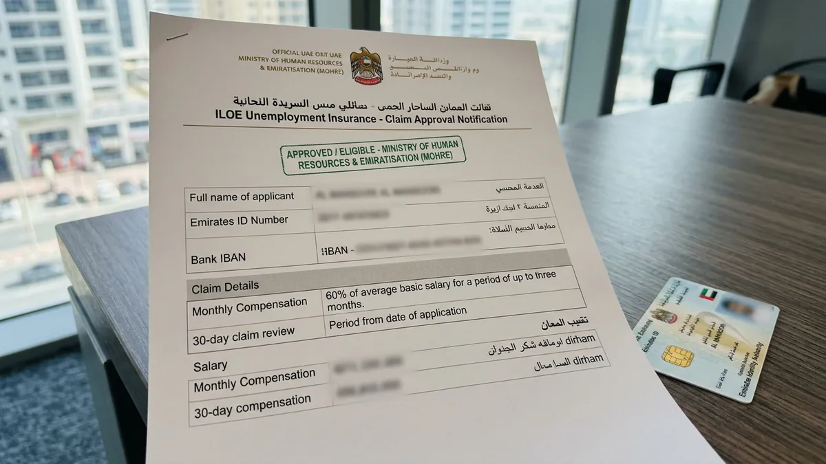 Official UAE ILOE unemployment insurance claim approval notification on a desk with redacted confidential details